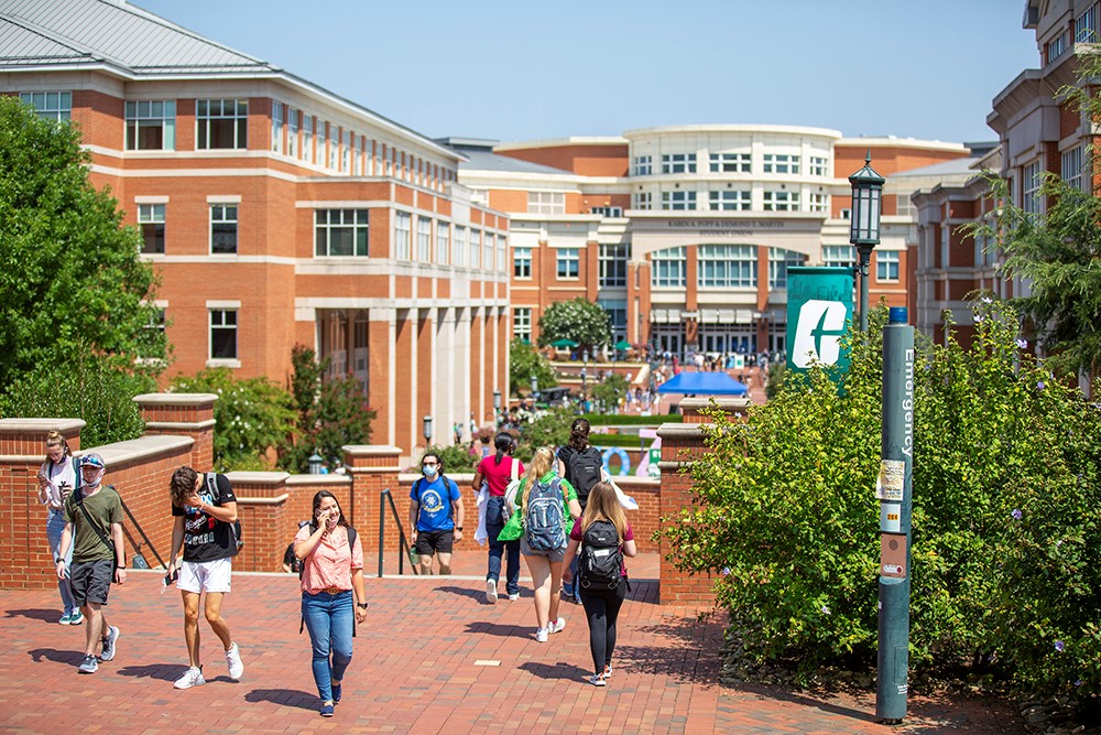 Student walking on UNC Charlotte campus on a sunny day