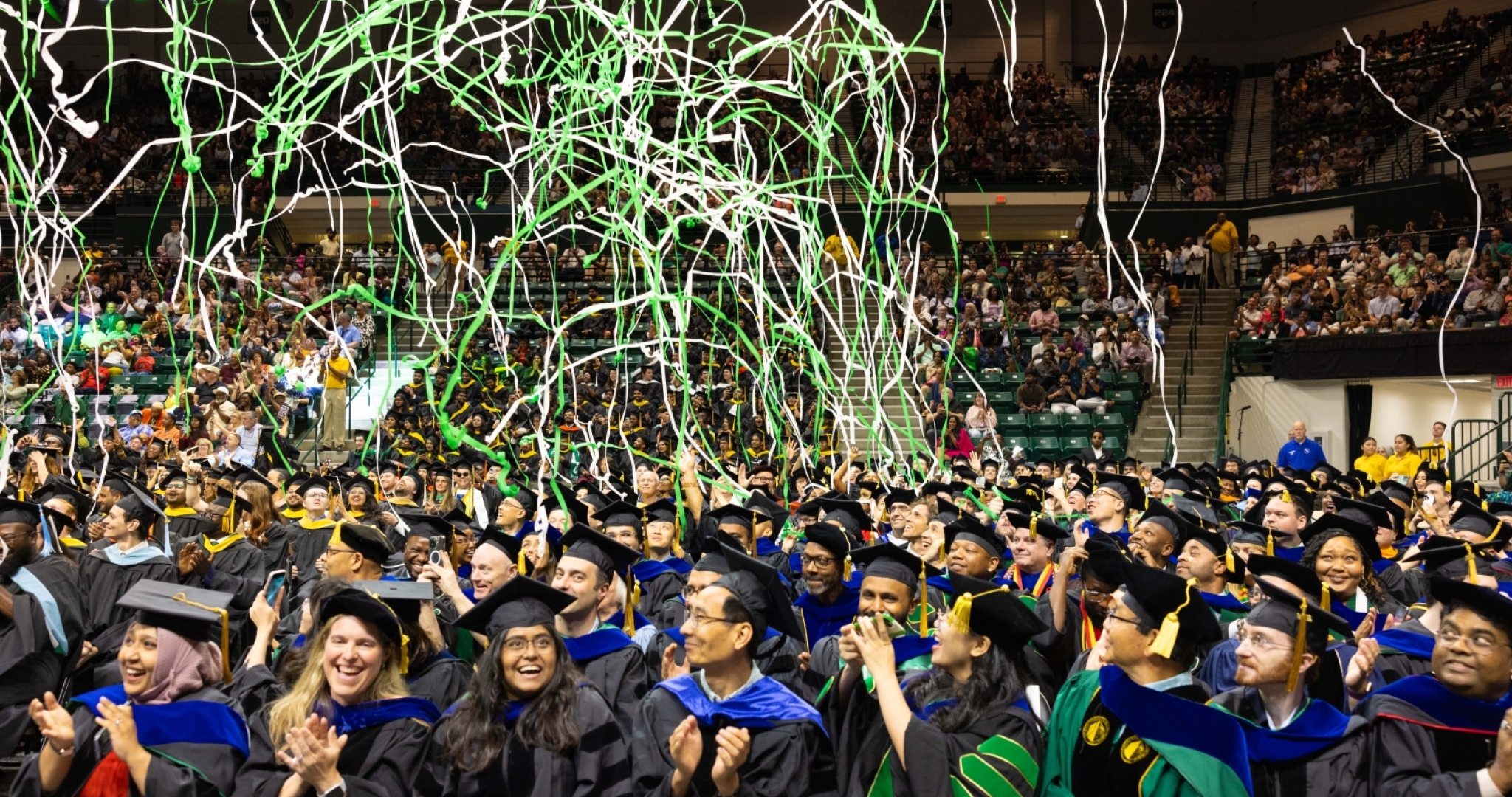 Graduate students celebrate during commencement with confetti overhead