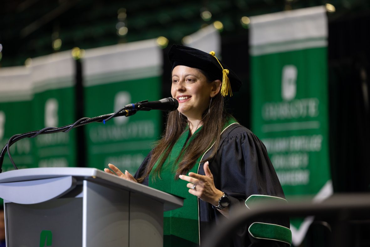 Jennifer Adelhardt, wearing her doctoral regalia, presenting her class commencement speech at the stage podium.
